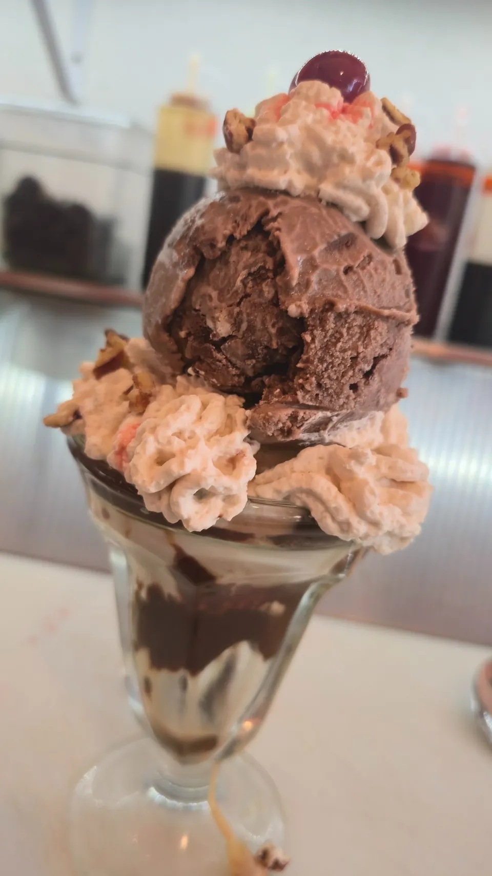 Rich chocolate ice cream sundae with whipped cream, cherry, and hot fudge