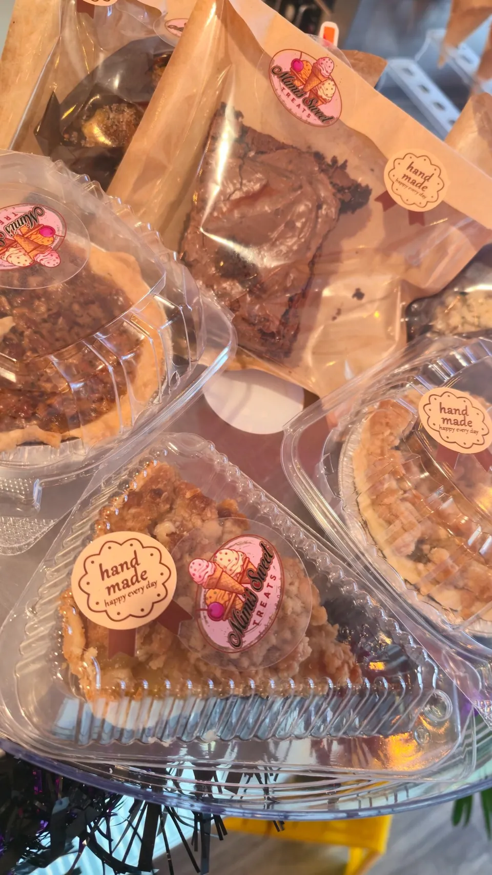 Assorted hand-made packaged baked goods with Mimi's Sweet Treats labels — brownies and pies