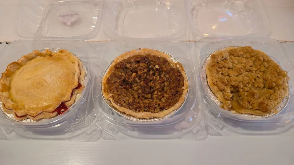 Three individual pies side by side — cherry, pecan, and streusel apple