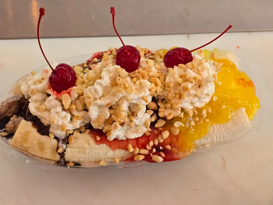 Banana split with three cherries, whipped cream, pineapple, and strawberry toppings