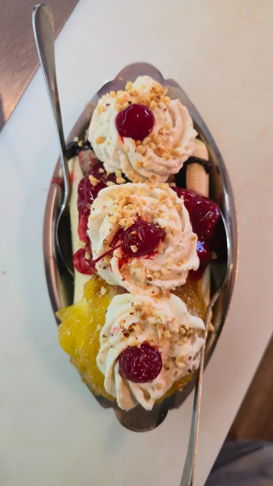 Banana split served in a retro silver boat dish with whipped cream rosettes and maraschino cherries