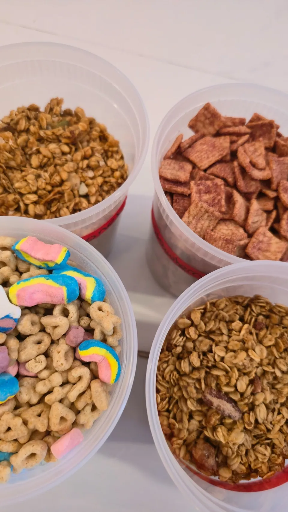 Four containers of mix-in toppings: Lucky Charms, Cinnamon Toast Crunch, granola, and Cheerios